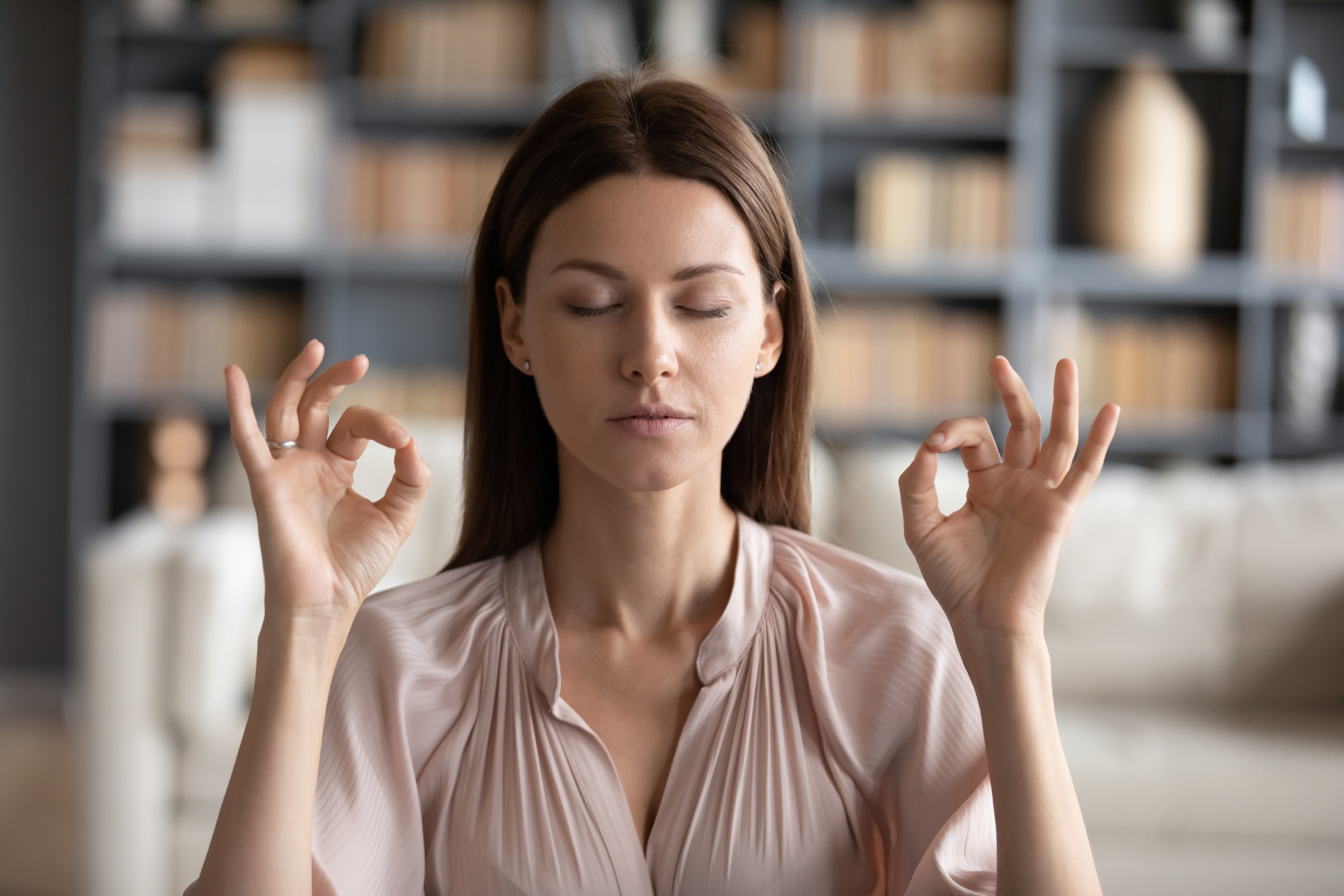 Tranquil mindful young woman managing stress at workplace.